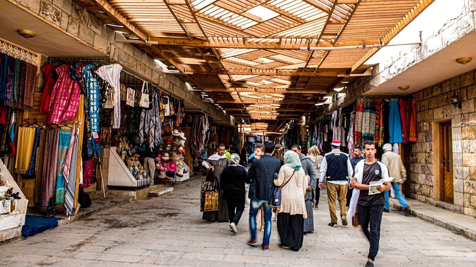 Textiles and visitors in a covered market in the Luxor region