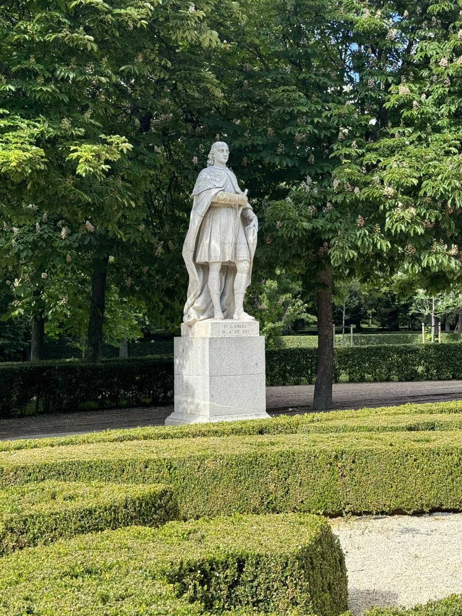 Stone statue beside a formal garden path.