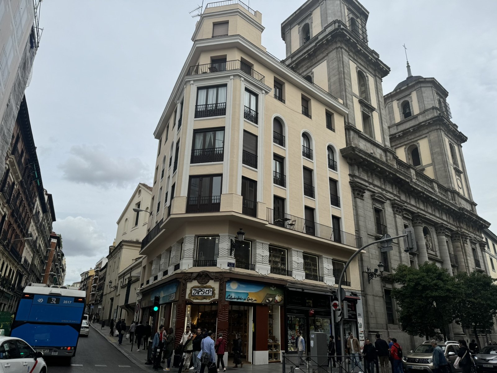 Corner building and church towers above a busy street.