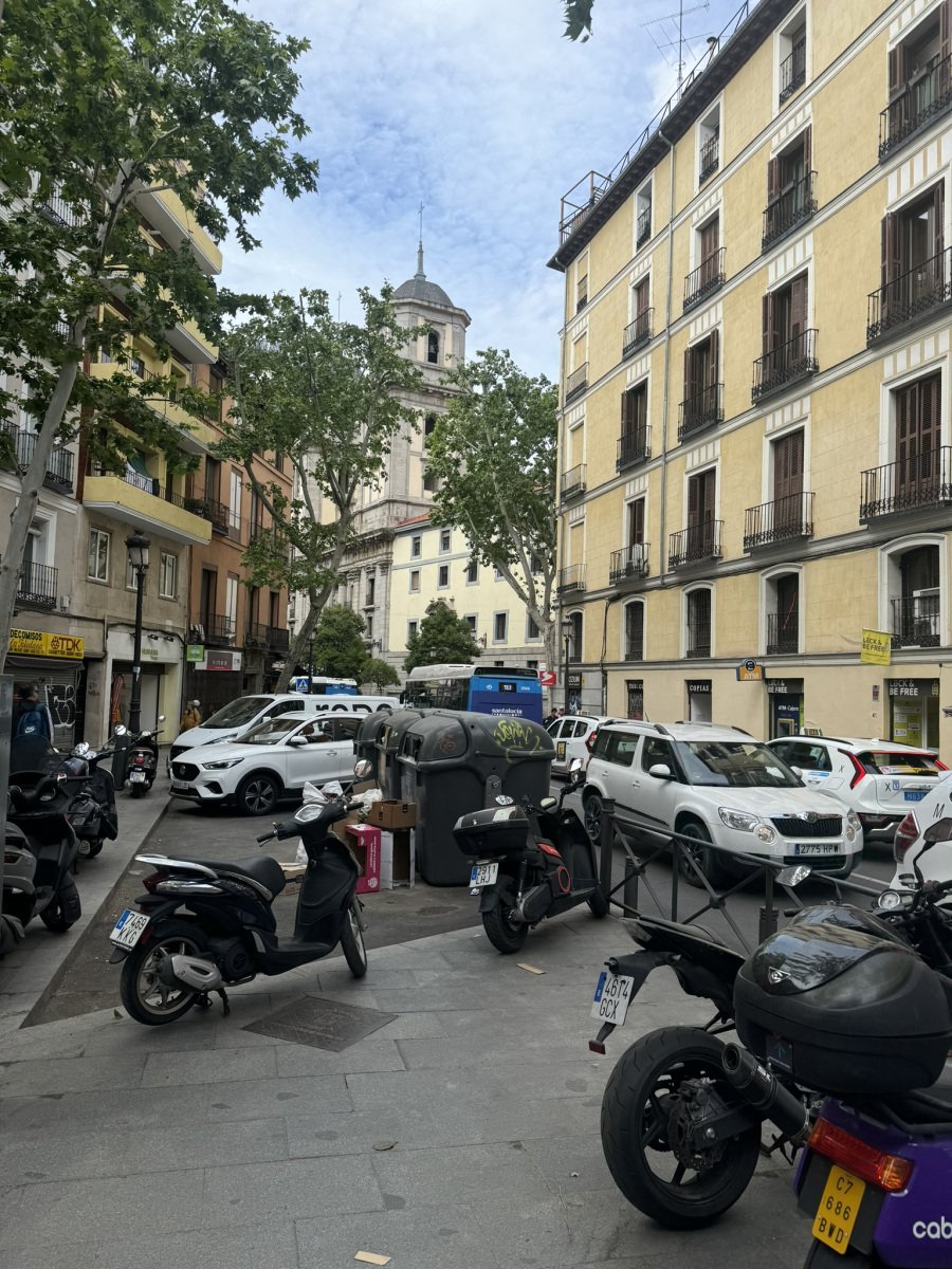 Parked scooters and cars along a Madrid street.