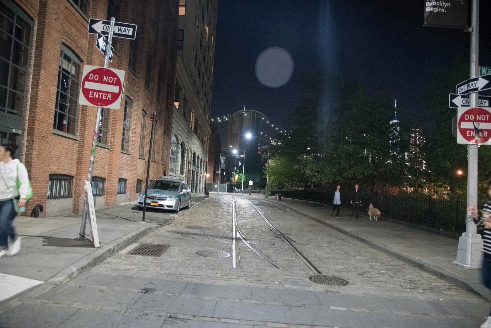 Rail tracks and stone paving lead through DUMBO at night.
