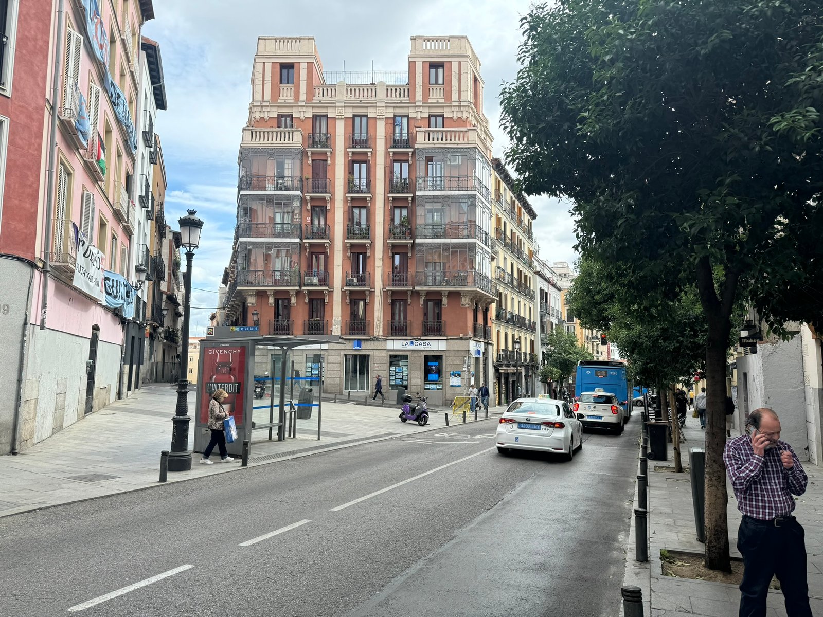 Madrid street with a brick apartment façade and traffic.