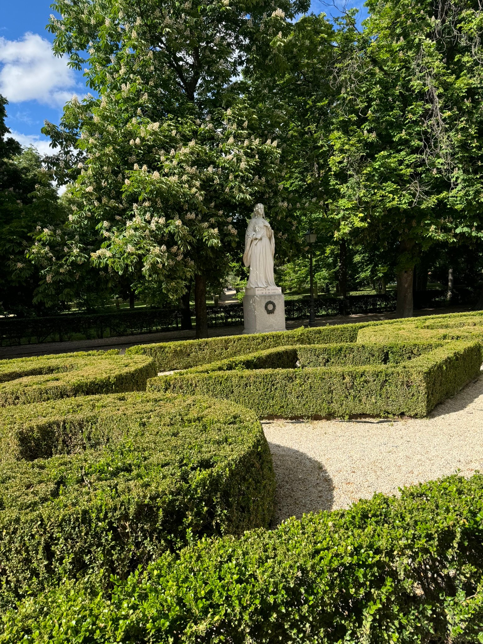 Formal garden hedges around a stone statue.