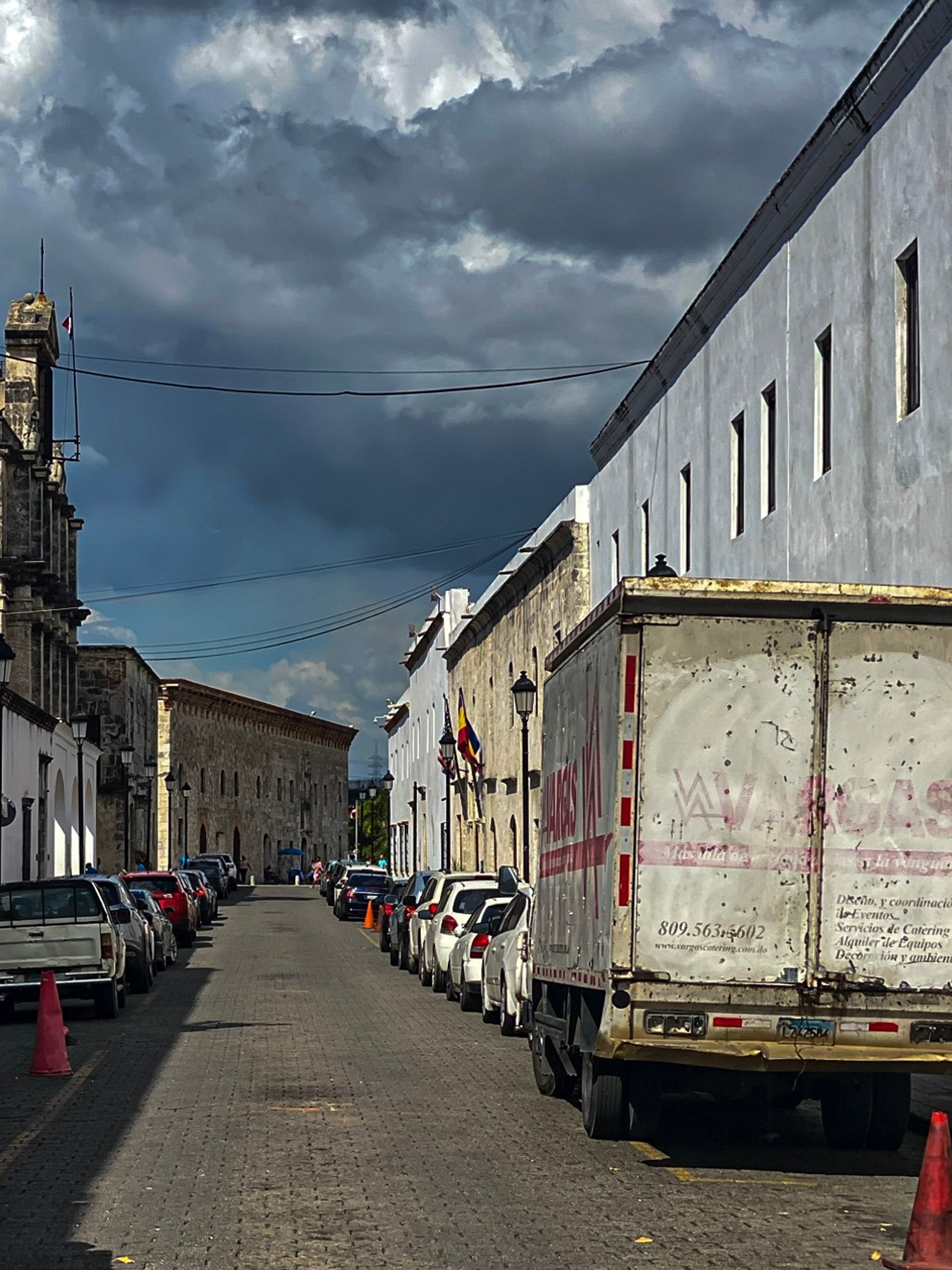 Dark clouds over a street with parked vehicles.